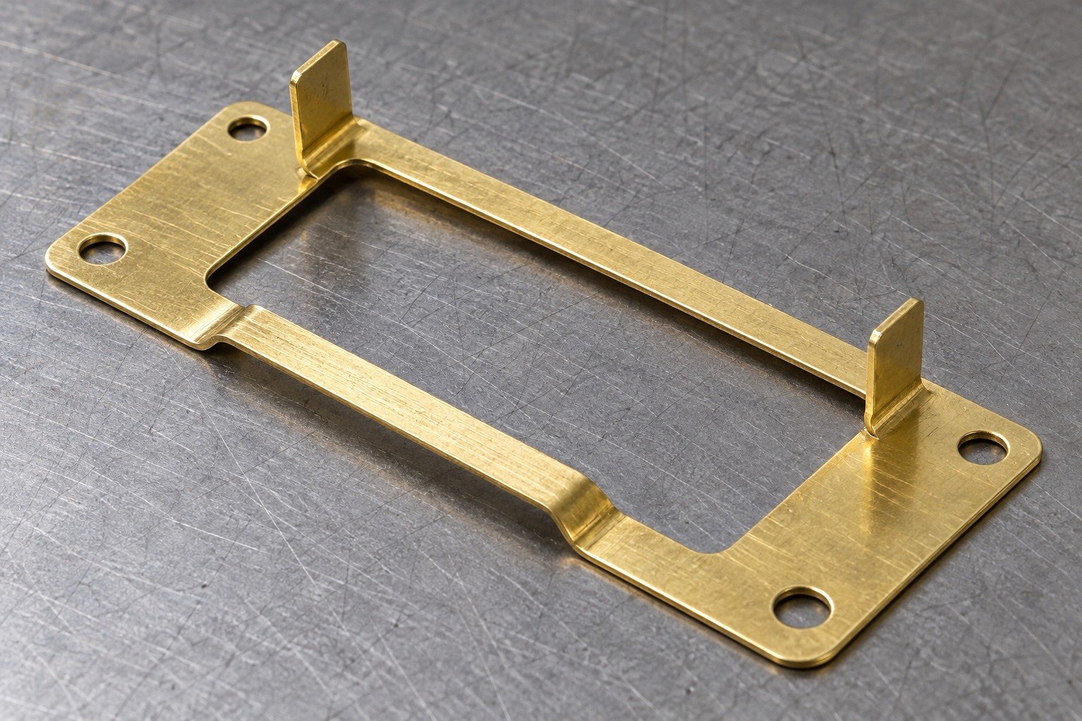 Thin yellow brass stamped rectangular connector frame with large central pierced rectangular opening, two raised folded locating tabs, four small mounting holes and one shallow offset step; visibly thin sheet edges, no machined block — illustrative generated component concept