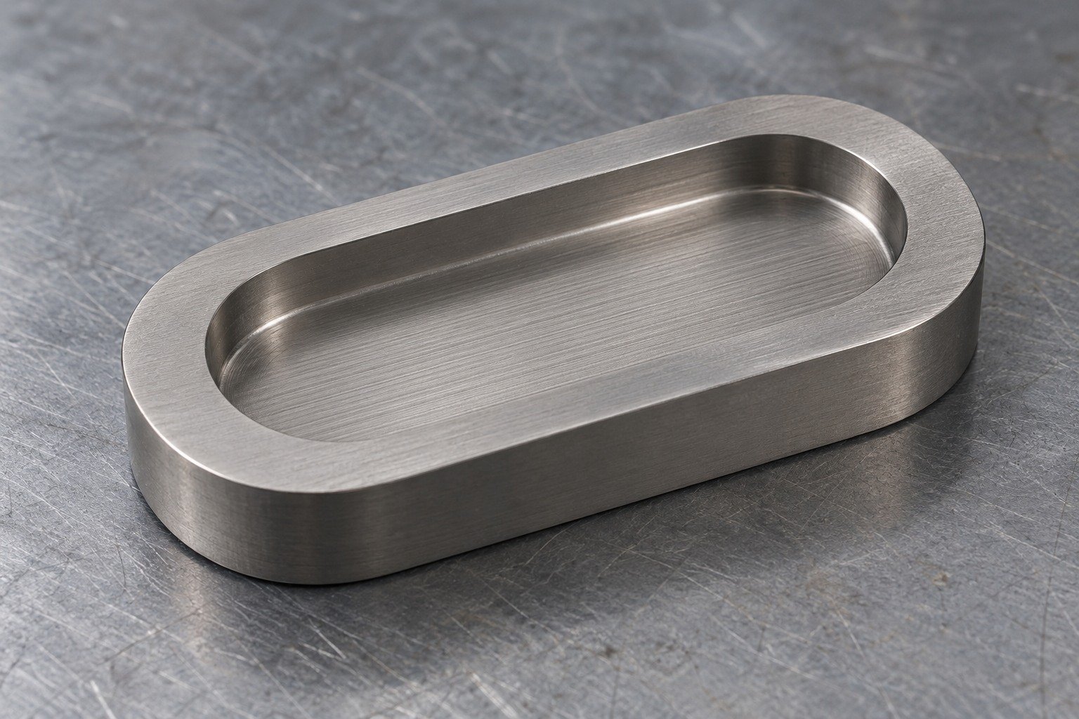 Grey titanium obround coupon with shallow recessed pocket and subtle parallel machining tool marks,no coloured coating. — illustrative generated component concept